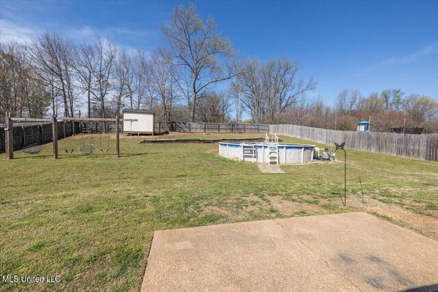 view of yard with a fenced backyard, a patio, an outdoor structure, and a fenced in pool