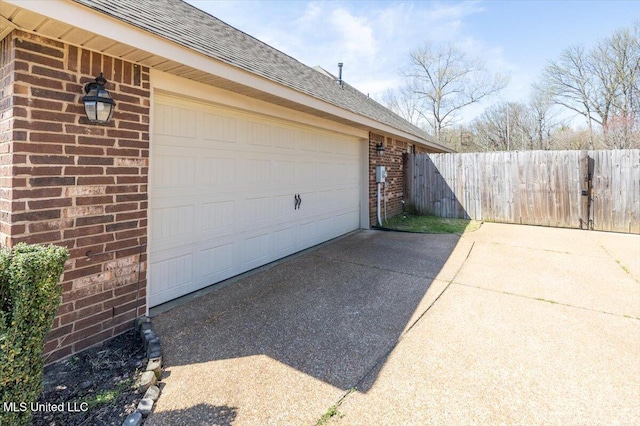 garage featuring concrete driveway and fence