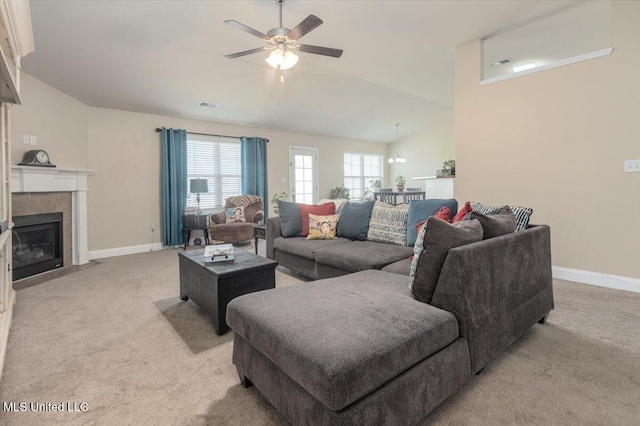 living room featuring vaulted ceiling, light colored carpet, visible vents, a ceiling fan, and a tile fireplace