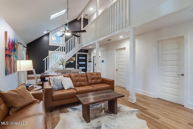 living room featuring ceiling fan, high vaulted ceiling, baseboards, wood finished floors, and stairway