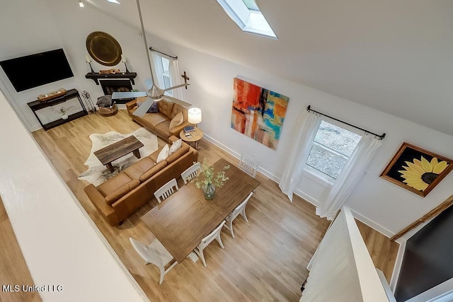 living room featuring baseboards, a skylight, and wood finished floors