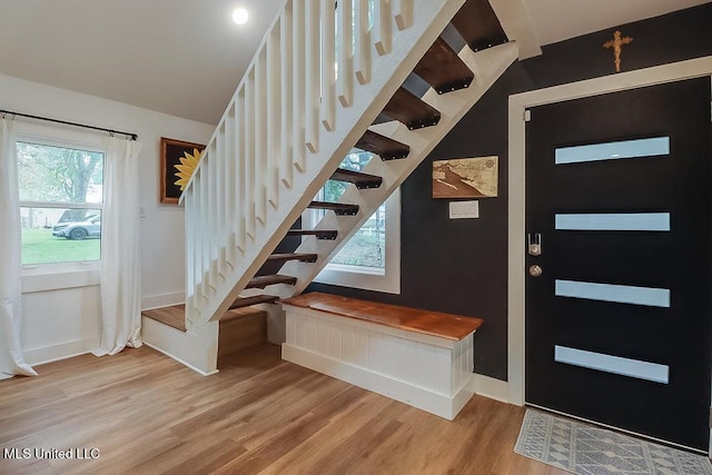 interior space with stairs, baseboards, lofted ceiling, and light wood-style floors