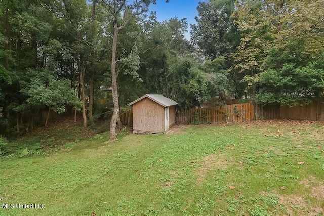 view of yard with a fenced backyard, a shed, and an outbuilding