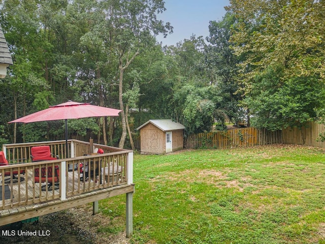 view of yard featuring a storage shed, an outbuilding, a wooden deck, and a fenced backyard