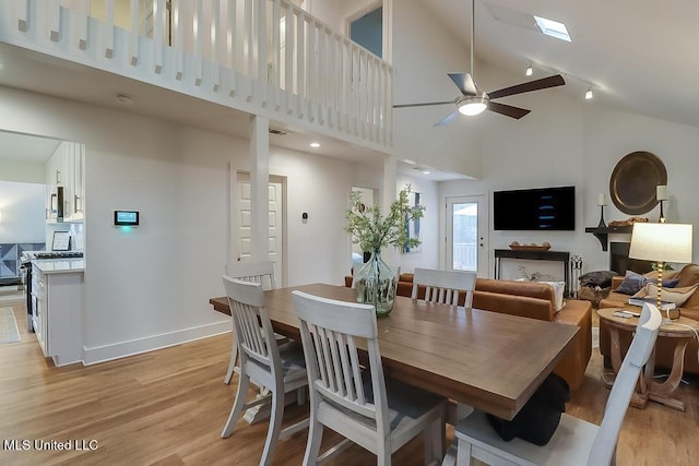 dining space with high vaulted ceiling, light wood-style flooring, a ceiling fan, baseboards, and visible vents