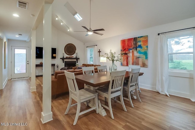 dining space featuring light wood-style floors, plenty of natural light, lofted ceiling, and visible vents