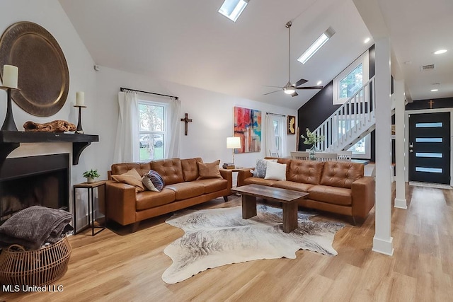 living room featuring visible vents, light wood-style flooring, a fireplace, and stairway