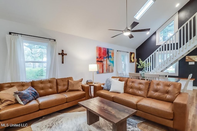 living room featuring a ceiling fan, high vaulted ceiling, wood finished floors, and stairway