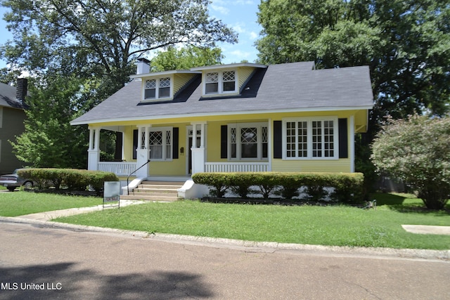 bungalow-style home with covered porch, a chimney, and a front yard