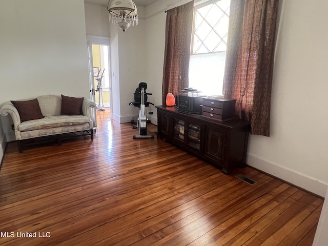 sitting room featuring hardwood / wood-style floors, an inviting chandelier, baseboards, and visible vents