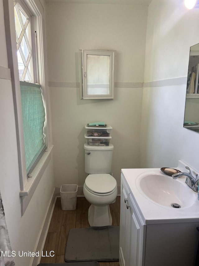 bathroom with toilet, vanity, baseboards, and wood finished floors