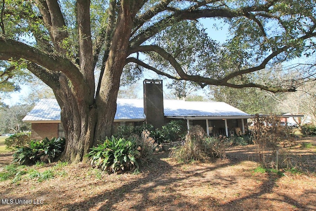 view of side of home featuring a chimney and metal roof