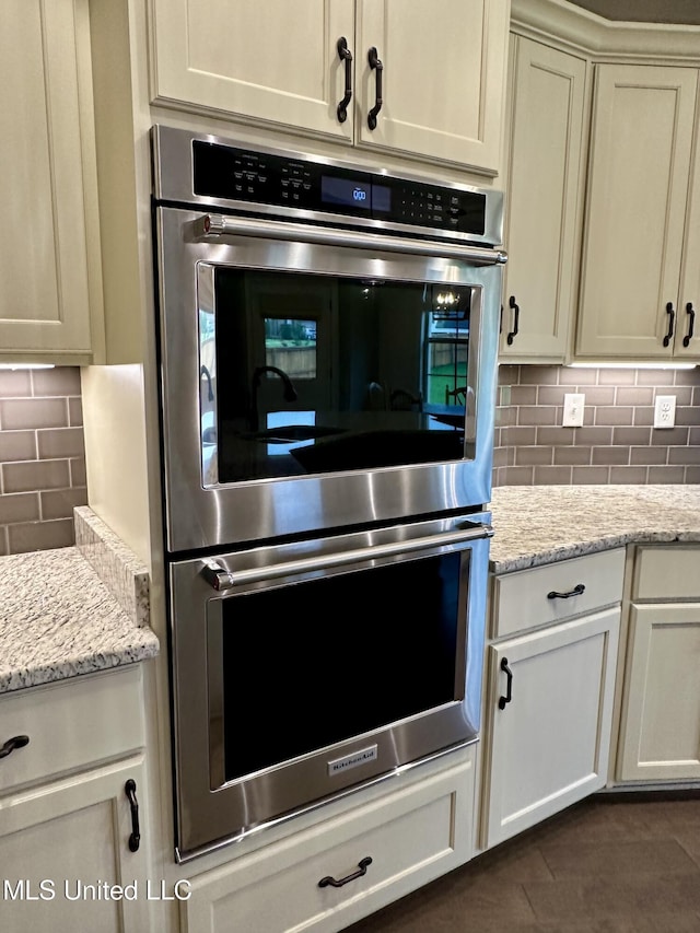4049 Courtyard Dr, Southaven, MS 38671 - kitchen featuring stainless steel double oven, decorative backsplash, and light stone counters