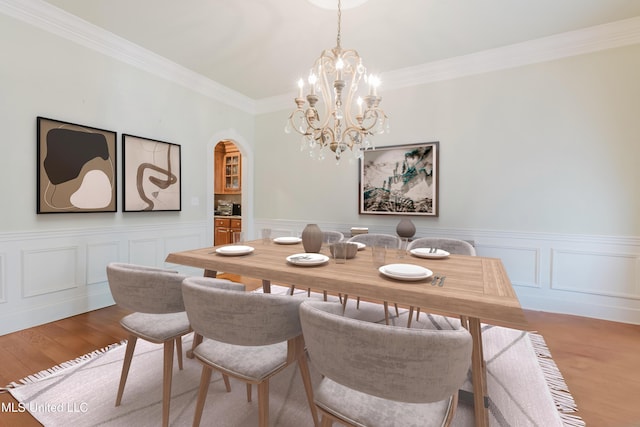 104 Overbrook Hl, Ridgeland, MS 39157 - dining room featuring arched walkways, a chandelier, ornamental molding, wood finished floors, and wainscoting