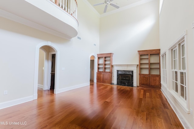 104 Overbrook Hl, Ridgeland, MS 39157 - unfurnished living room featuring a towering ceiling, arched walkways, ceiling fan, wood finished floors, and a premium fireplace