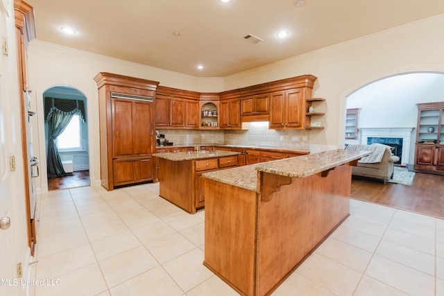 104 Overbrook Hl, Ridgeland, MS 39157 - kitchen featuring open shelves, brown cabinets, arched walkways, a peninsula, and crown molding