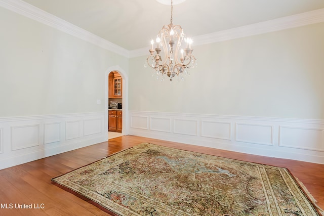 104 Overbrook Hl, Ridgeland, MS 39157 - unfurnished dining area with arched walkways, a chandelier, crown molding, wainscoting, and light wood-type flooring