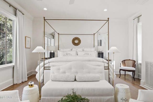 bedroom featuring visible vents, multiple windows, ornamental molding, and wood finished floors