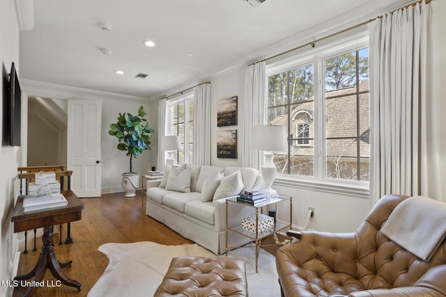 living area with recessed lighting, visible vents, ornamental molding, wood finished floors, and baseboards