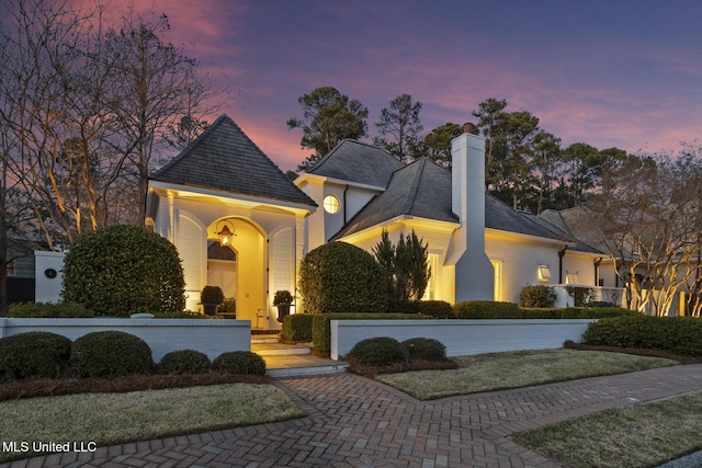 view of front of home with decorative driveway and a chimney