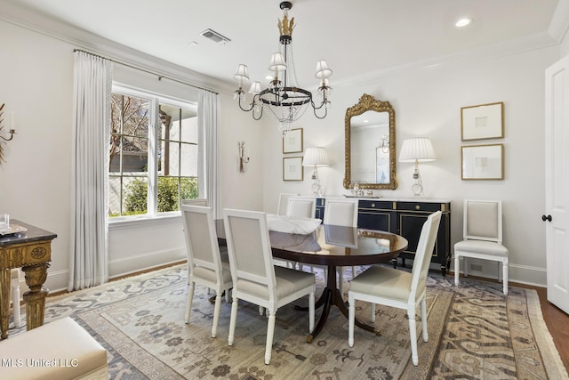 dining area with crown molding, a notable chandelier, visible vents, wood finished floors, and baseboards