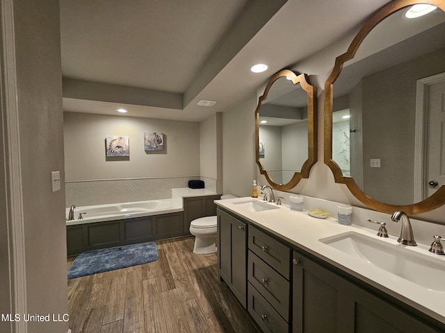 bathroom with a bathing tub, toilet, vanity, and hardwood / wood-style flooring