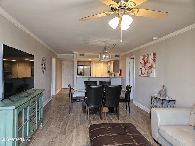 dining room featuring ceiling fan with notable chandelier, hardwood / wood-style flooring, and ornamental molding