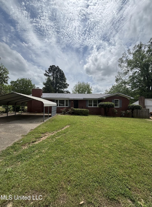 ranch-style home featuring driveway, metal roof, a detached carport, and a front lawn