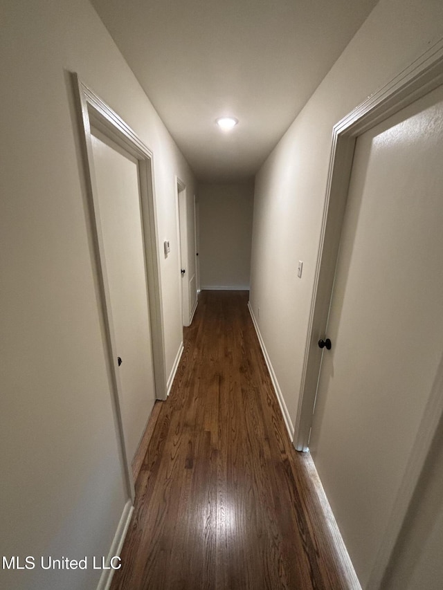corridor with baseboards and dark wood-style floors