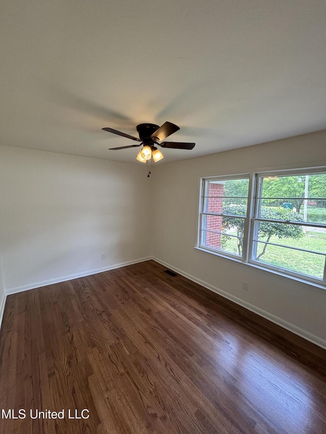 spare room with baseboards, ceiling fan, dark wood-style floors, and visible vents