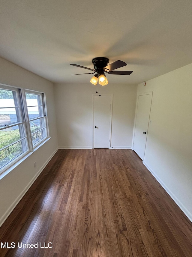 interior space with baseboards, dark wood-style floors, and ceiling fan