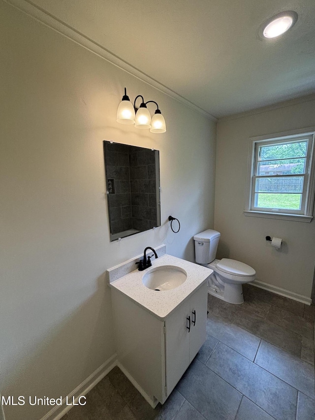 bathroom with vanity, ornamental molding, baseboards, and toilet