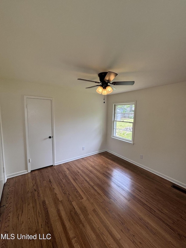 spare room with ceiling fan, dark wood finished floors, baseboards, and visible vents
