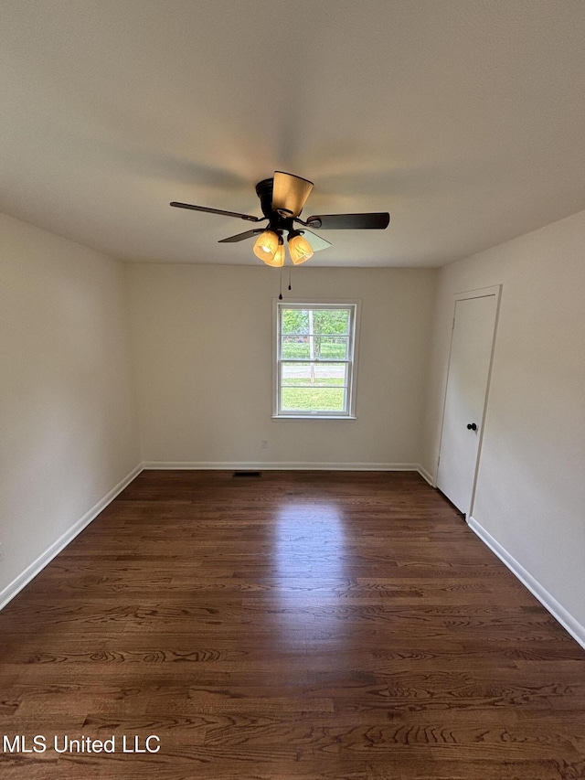 unfurnished room featuring dark wood-style flooring, a ceiling fan, and baseboards