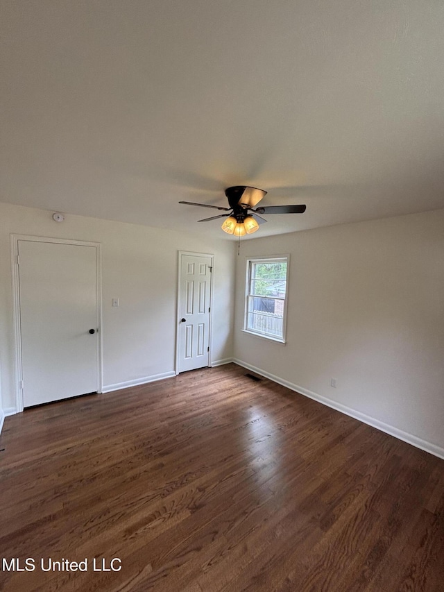 unfurnished bedroom with baseboards, dark wood finished floors, ceiling fan, and a closet
