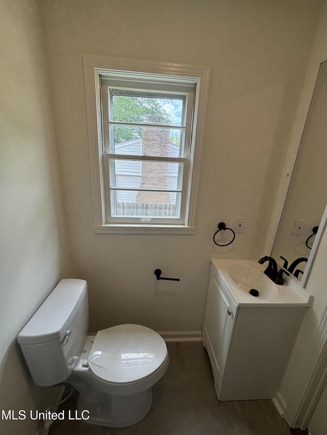 bathroom featuring vanity, baseboards, tile patterned floors, and toilet