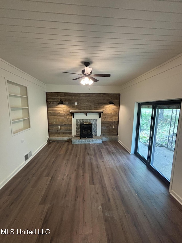unfurnished living room featuring visible vents, baseboards, a fireplace with raised hearth, built in shelves, and a ceiling fan