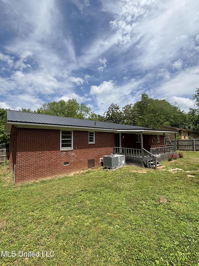rear view of property with crawl space, central air condition unit, brick siding, fence, and a yard