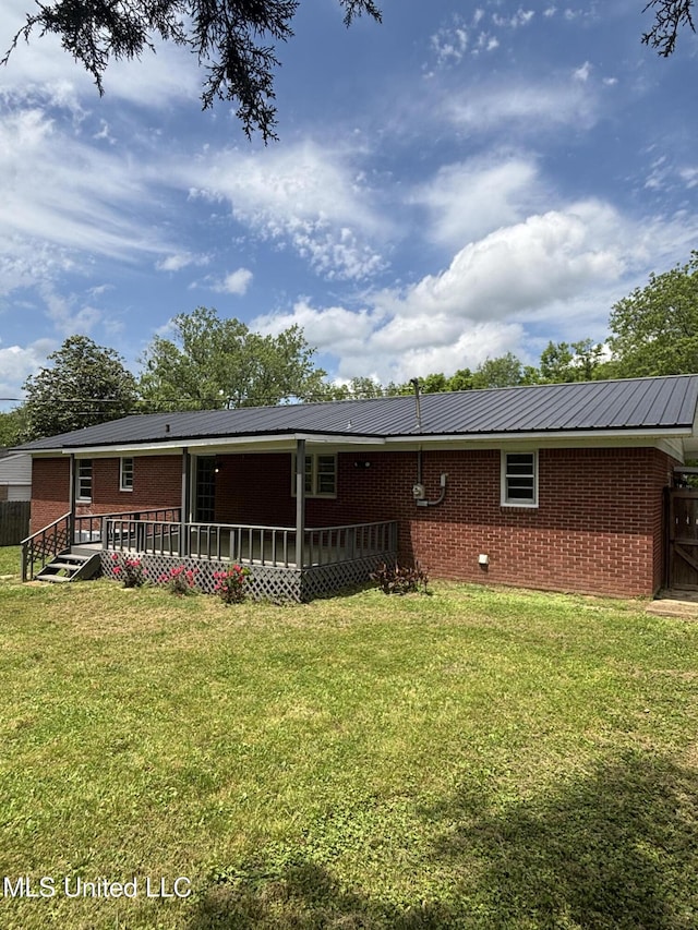 back of house with brick siding and a yard