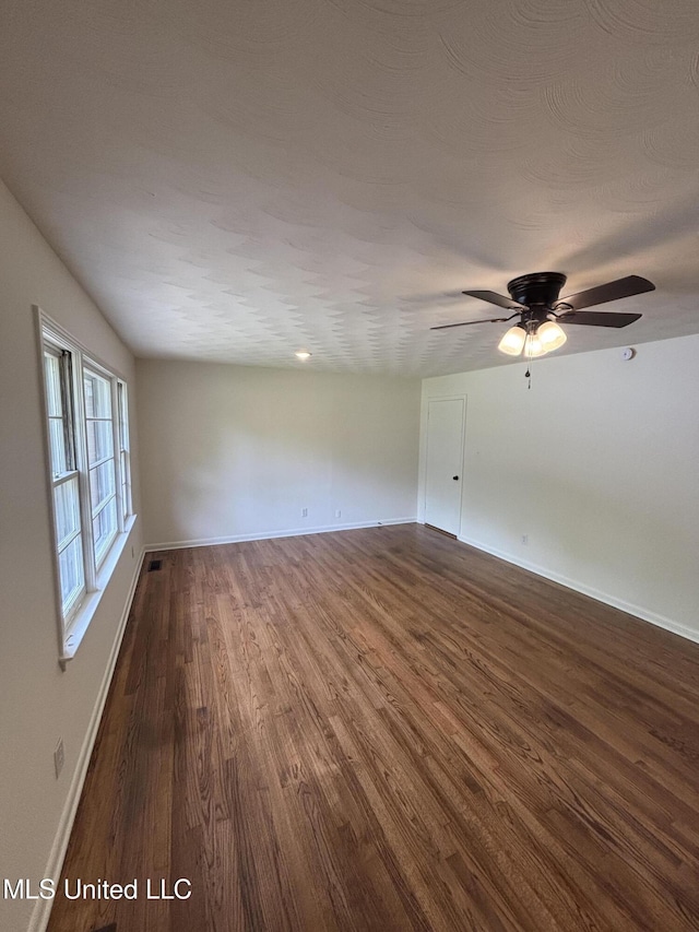 unfurnished room featuring baseboards, ceiling fan, and dark wood-style flooring