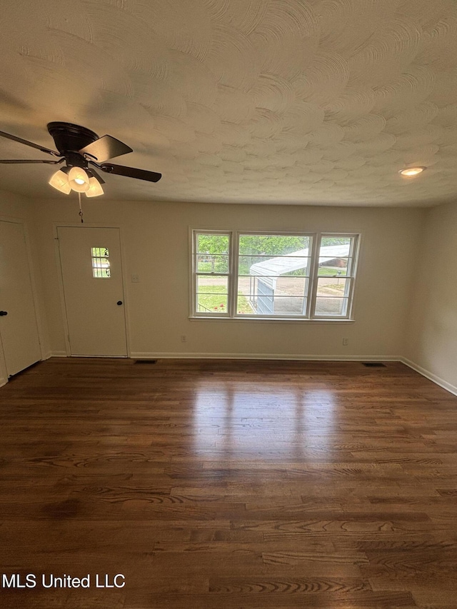 interior space with baseboards, a ceiling fan, and dark wood-style flooring