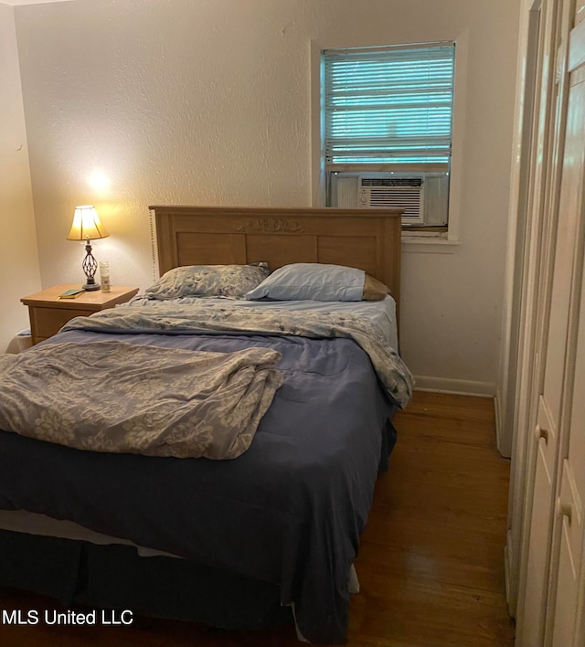 bedroom with cooling unit and dark hardwood / wood-style flooring