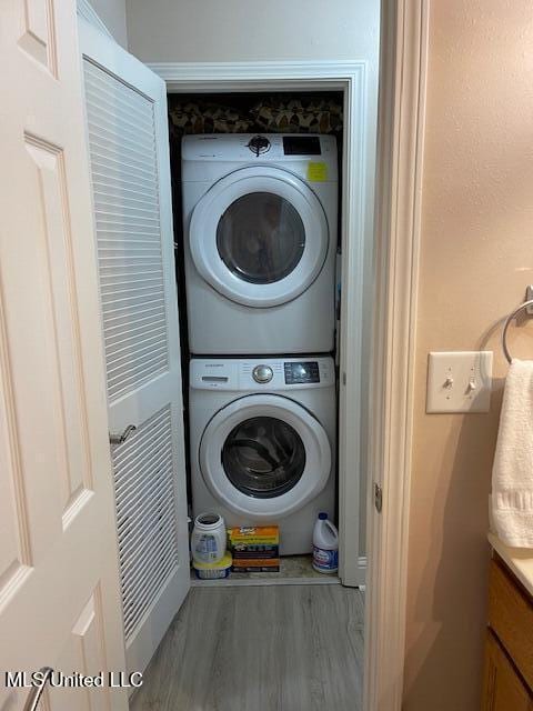 laundry room featuring stacked washer and clothes dryer and hardwood / wood-style floors