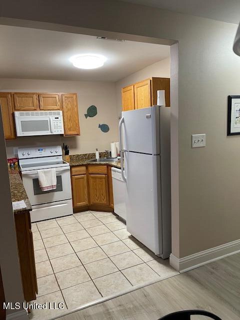 kitchen featuring light tile patterned flooring, sink, and white appliances