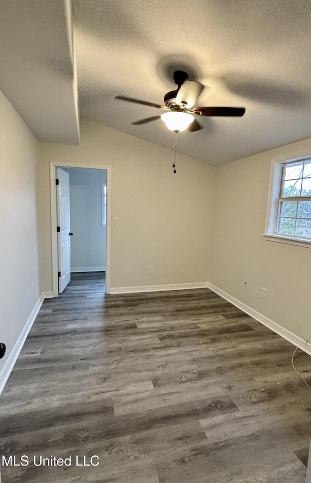 spare room with ceiling fan, vaulted ceiling, dark wood-type flooring, and a textured ceiling