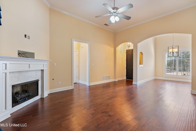 unfurnished living room featuring a tiled fireplace, crown molding, dark hardwood / wood-style floors, and ceiling fan