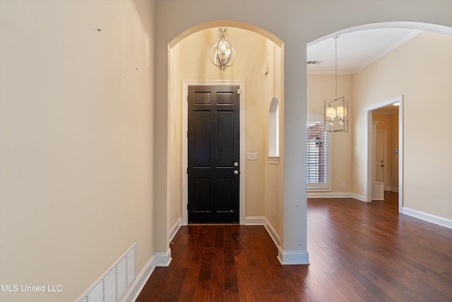 entrance foyer featuring crown molding, dark wood-type flooring, and an inviting chandelier