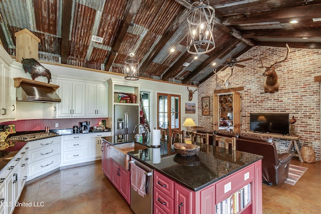 kitchen featuring range hood, stainless steel appliances, brick wall, and an island with sink