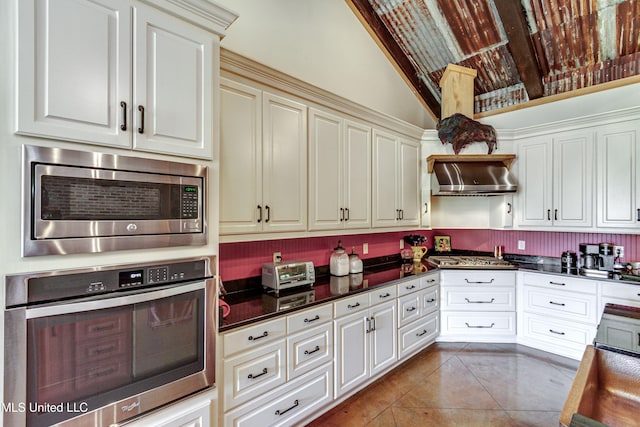 kitchen with appliances with stainless steel finishes, ventilation hood, tile patterned floors, and lofted ceiling