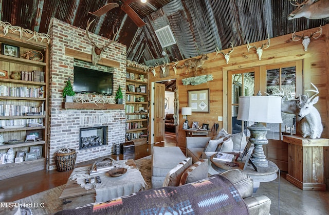 living room featuring built in shelves, wood walls, a fireplace, and high vaulted ceiling